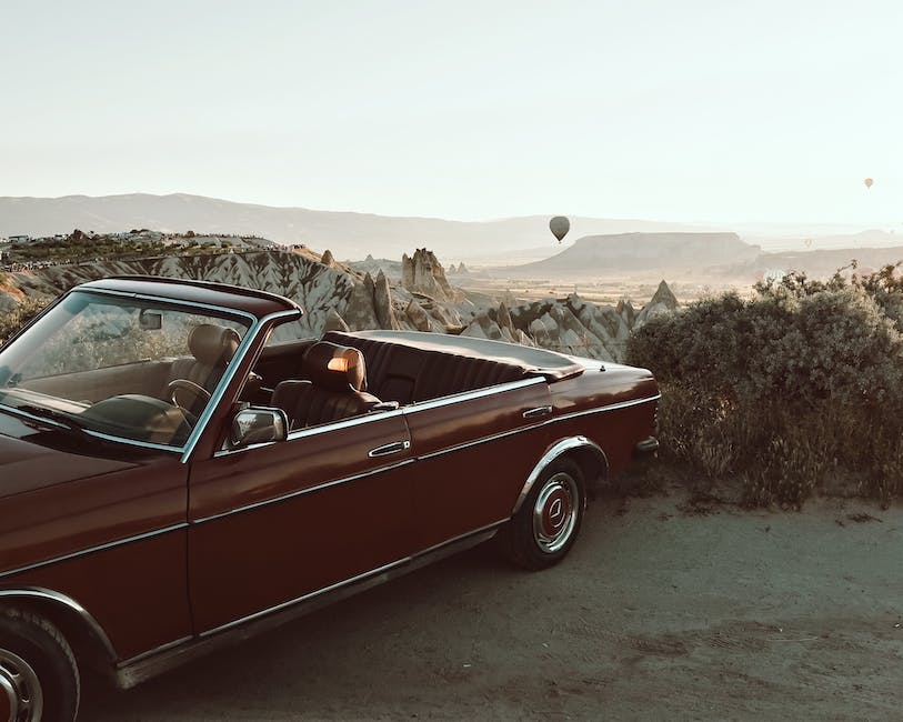 A vintage classic car parked in front of a sunset