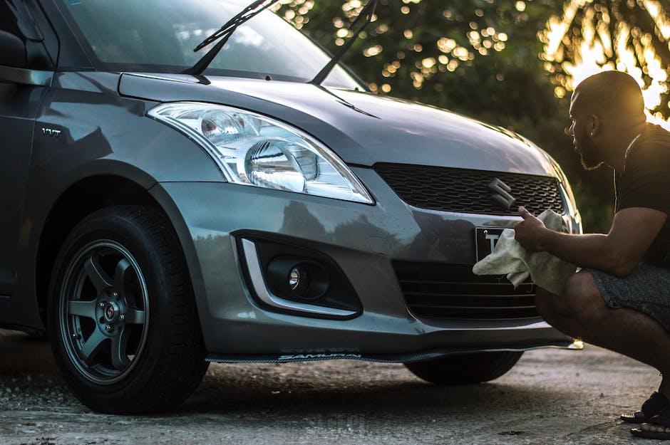A visual image of a person cleaning the exterior of a car with detailing products